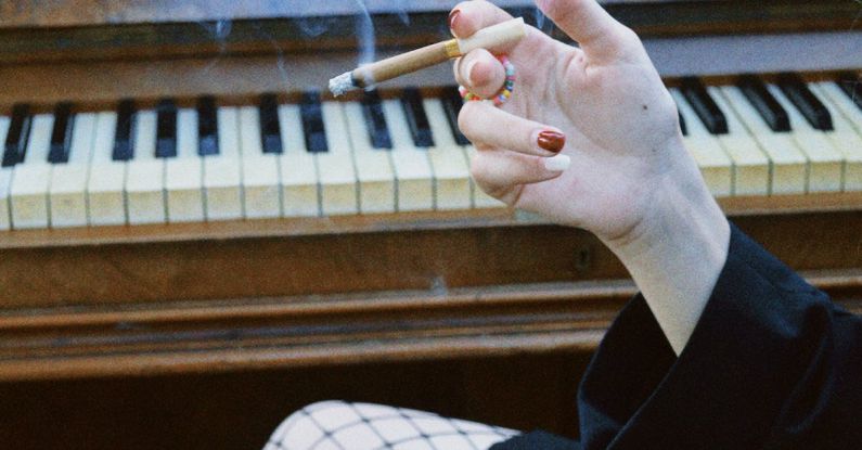 E-Cigarettes - Woman Sitting by the Piano and Smoking a Cigarette