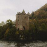 Loch Ness - Scenic view of ancient masonry castle exterior on mountain with trees near Loch Ness lake under misty sky